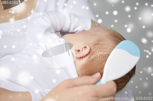 Image of close up of mother brushing newborn baby hair