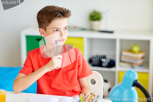 Image of student boy with pen and notebook thinking at home