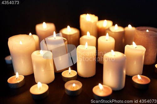 Image of candles burning in darkness over black background