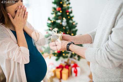 Image of husband giving christmas present to pregnant wife