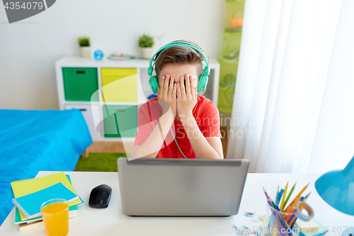 Image of boy in headphones playing video game on laptop