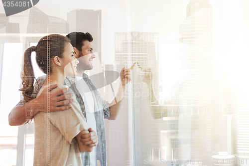 Image of happy couple looking through window at new home