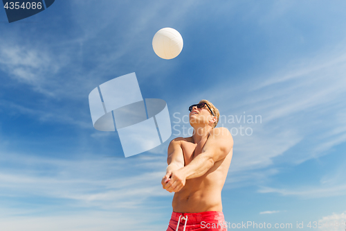 Image of young man with ball playing volleyball on beach
