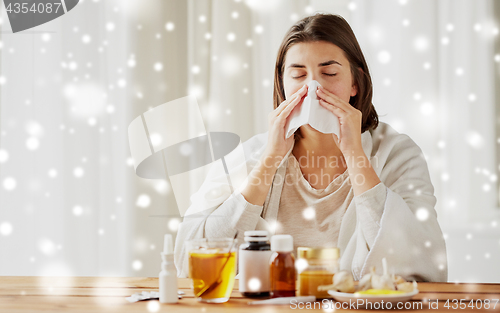 Image of sick woman with medicine blowing nose to wipe