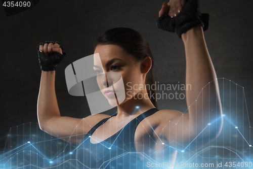 Image of young woman flexing muscles in gym