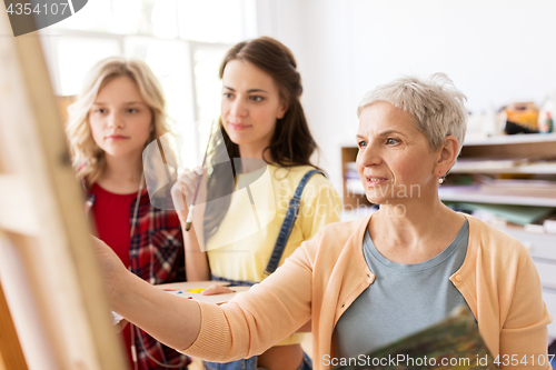 Image of women with easel and palettes at art school