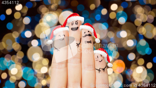 Image of close up of fingers in santa hats at christmas