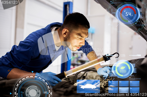 Image of mechanic man with lamp repairing car at workshop