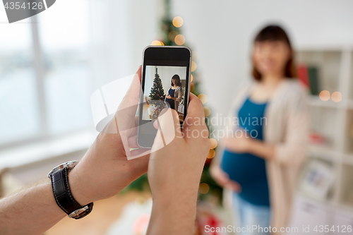 Image of husband photographing pregnant fife at christmas