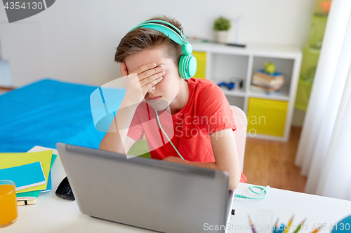 Image of boy in headphones playing video game on laptop