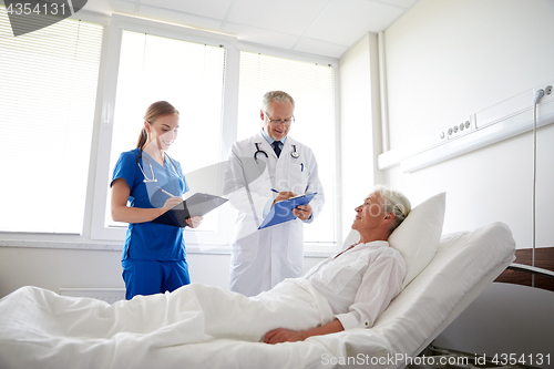 Image of doctor and nurse visiting senior woman at hospital