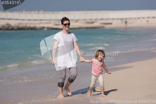 Image of mother and daughter running on the beach