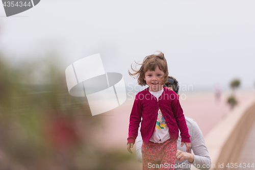 Image of mother and cute little girl on the promenade by the sea