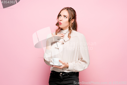 Image of The serious frustrated young beautiful business woman on pink background