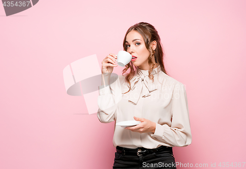 Image of The serious frustrated young beautiful business woman on pink background