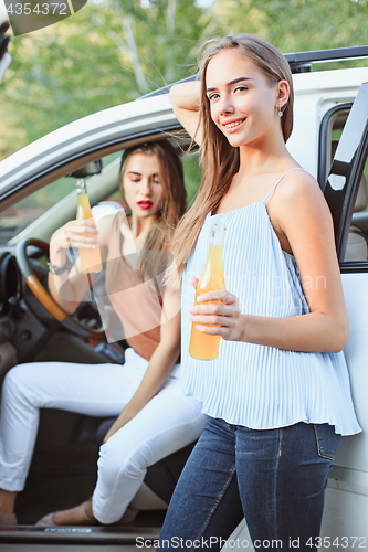 Image of The young women in the car smiling and drinking juice