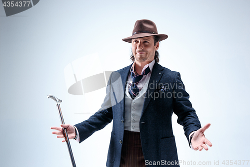 Image of The mature man in a suit and hat holding cane.