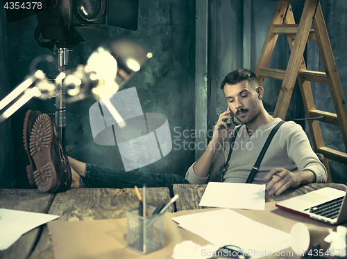 Image of Portrait of a bearded businessman who is working with his notebook at loft studio.