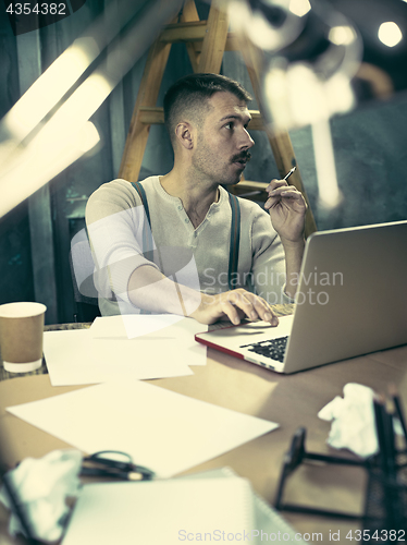 Image of Portrait of a bearded businessman who is checking details of his upcoming meeting in his notebook and typing.