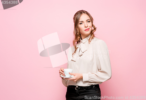 Image of The serious frustrated young beautiful business woman on pink background