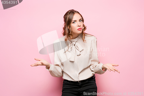 Image of The serious frustrated young beautiful business woman on pink background