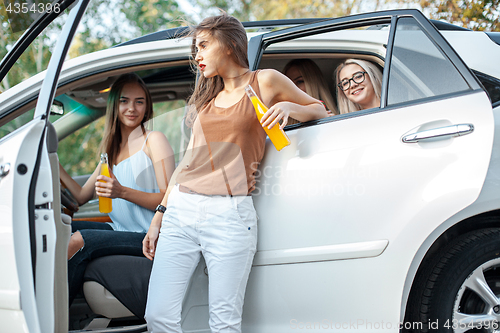 Image of The young women in the car smiling and drinking juice