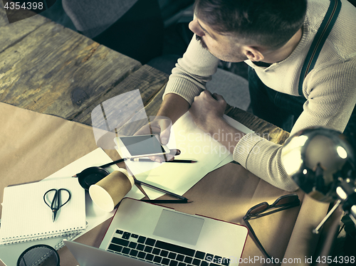 Image of Portrait of a bearded businessman who is working with his notebook at loft studio.