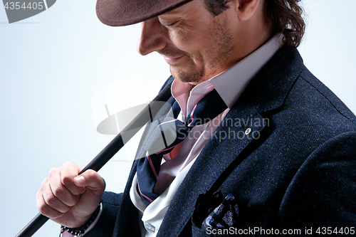 Image of The mature man in a suit and hat holding cane.