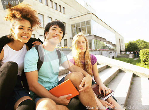 Image of cute group of teenages at the building of university with books huggings, back to school