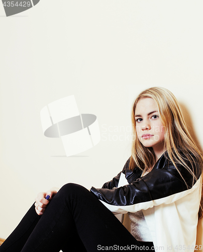 Image of young pretty teenage blond girl sitting on floor at home despair