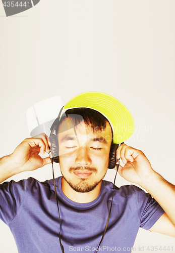 Image of young asian man in hat and headphones listening music on white b