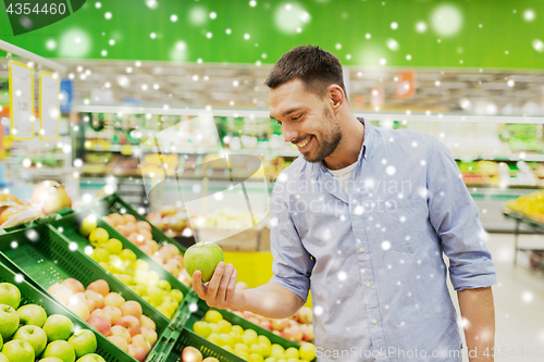 Image of happy man buying green apples at grocery store