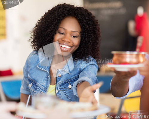 Image of happy woman with friends eating at restaurant