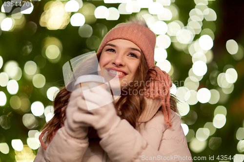 Image of happy woman with coffee over christmas lights