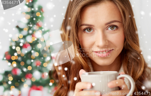 Image of close up of woman with tea cup over christmas tree