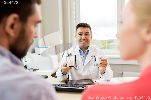 Image of doctor showing medicine to family couple at clinic