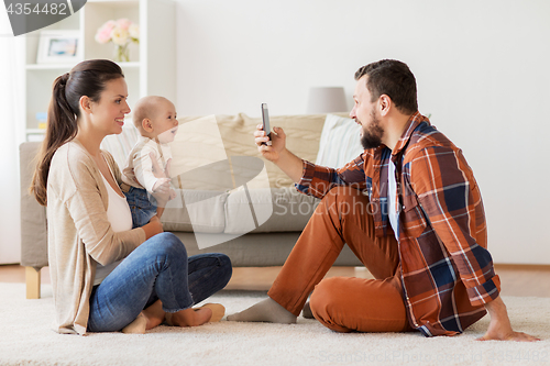 Image of happy family with baby photographing at home