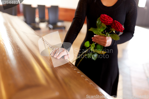 Image of woman with red roses and coffin at funeral