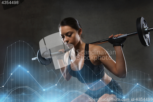 Image of young woman flexing muscles with barbell in gym