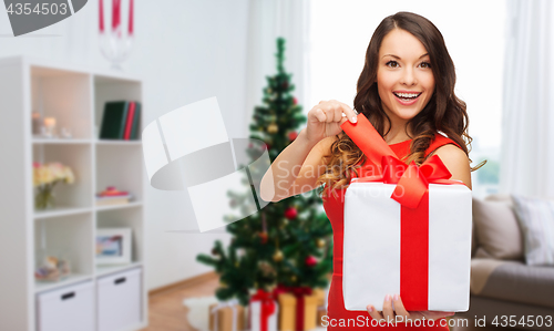 Image of smiling woman with christmas gift at home