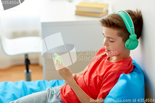 Image of happy boy with smartphone and headphones at home