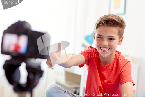 Image of happy boy with camera recording video at home