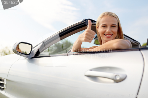 Image of happy young woman in convertible car thumbs up