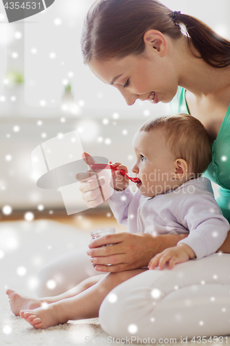 Image of mother with spoon feeding little baby at home