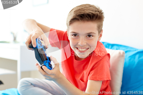 Image of happy boy with gamepad playing video game at home