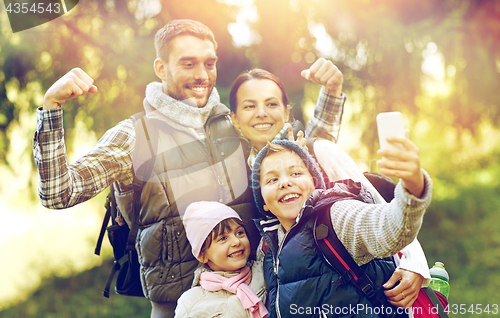 Image of family with backpacks taking selfie by smartphone