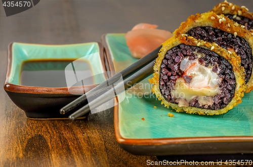 Image of Black sushi rolls served on turquoise plate