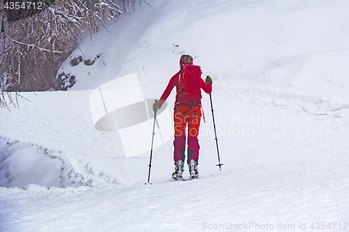 Image of Woman with skis walk by snow on the mountain