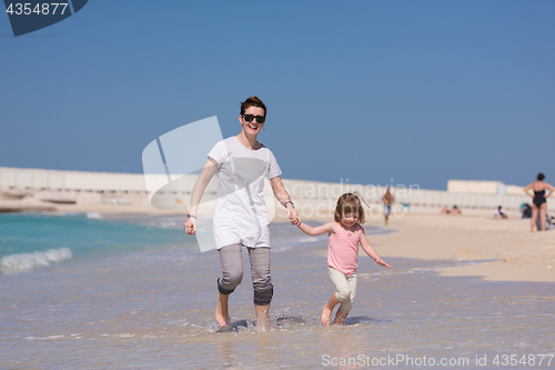 Image of mother and daughter running on the beach