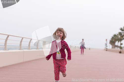 Image of mother and cute little girl on the promenade by the sea